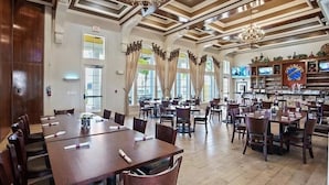 A spacious dining area with multiple tables and chairs, a bar area with shelves of bottles, and large windows allowing natural light. - Luxurious Villa - Near Disney - Golf Course (Davenport)