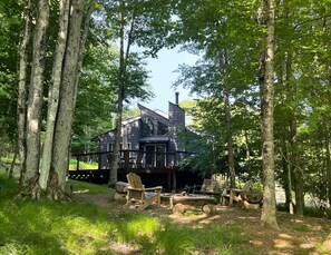 A rustic cabin with a sloped roof, surrounded by tall trees. - Dog-Friendly Mountain Hideaway ✺ Fenced Yard, Fire Pit, 2 Miles to Resort (Beech Mountain)