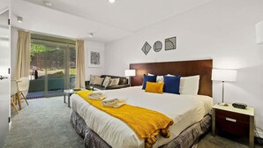 Habitación de hotel moderna con una cama grande, un escritorio y vistas al exterior.