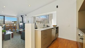 Una cocina moderna con un ventanal amplio, armarios de madera y una zona de comedor con mesa y sillas.