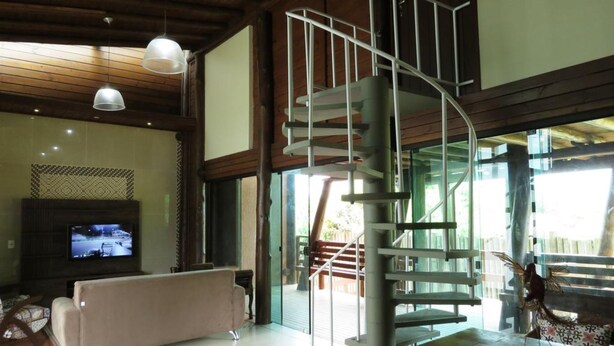 A modern interior with a spiral staircase, a flat-screen TV, and a sofa. - Morada Fenix Hospedagem (Palhoça)