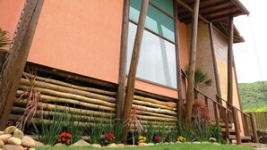 A building with a wooden exterior, large windows, and a covered porch area. - Morada Fenix Hospedagem (Palhoça)