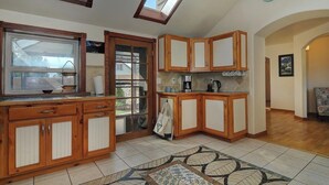 Una cocina con armarios de madera, un ventanal y piso de baldosas.