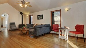 Un salón espacioso con pisos de madera, ventilador de techo, chimenea y comedor con mesa y sillas.