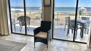 A balcony with a view of the ocean, a wicker chair, and a table with chairs. - 507 "A" Relaxing Bliss! Sept 13-20 Open! Book Soon! (Gulf Shroes)