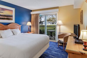 Una camera d'albergo con un letto grande, una scrivania con un televisore, una sedia e un balcone con vista sul paesaggio.