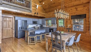 Una cocina amplia con una isla central, armarios grises y una chimenea de piedra.
