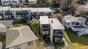 A modern residential building with multiple balconies, a flat roof, and a well-maintained lawn. - The Alps Studio - Cosy one bed right in the centre of Queenstown (Queenstown)