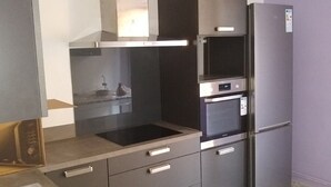 Una cocina moderna con horno empotrado, microondas y refrigerador.