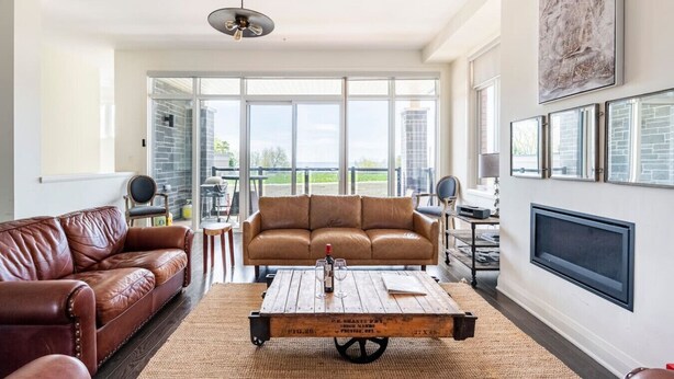 Een ruime woonkamer met een leren bank, een houten salontafel en een open haard.