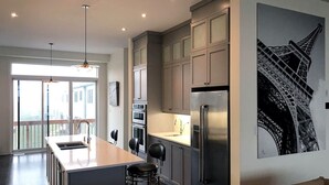 Een moderne keuken met een centraal eiland, roestvrijstalen apparatuur en een groot raam voor natuurlijk licht.