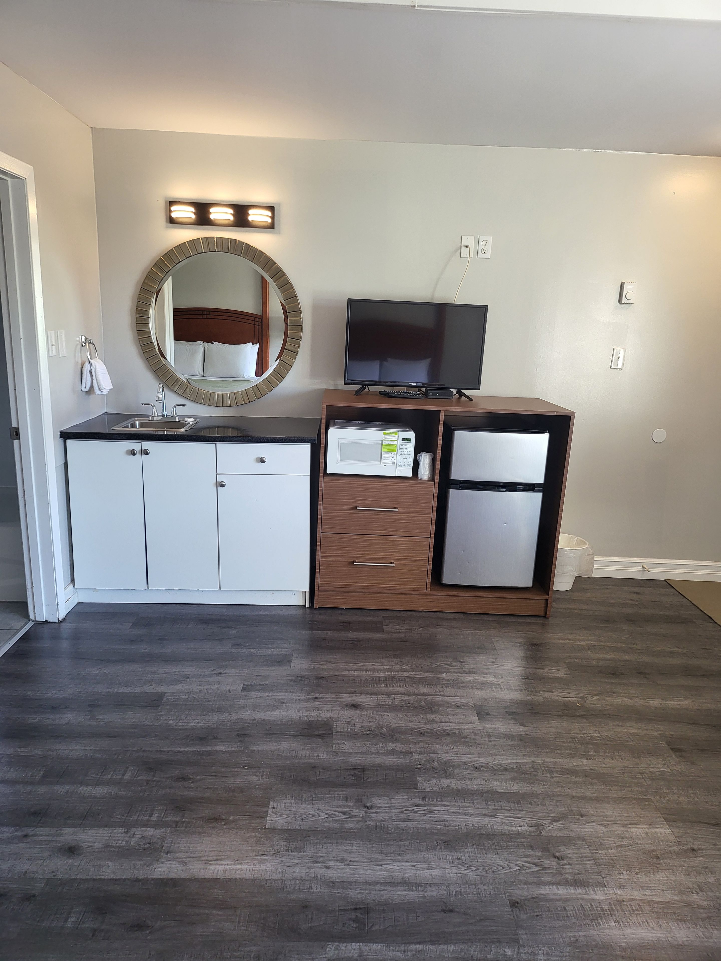 A modern bathroom with a vanity, sink, mirror, and a flat-screen TV.