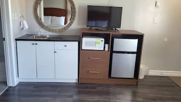 A modern bathroom with a vanity, sink, mirror, and a flat-screen TV.