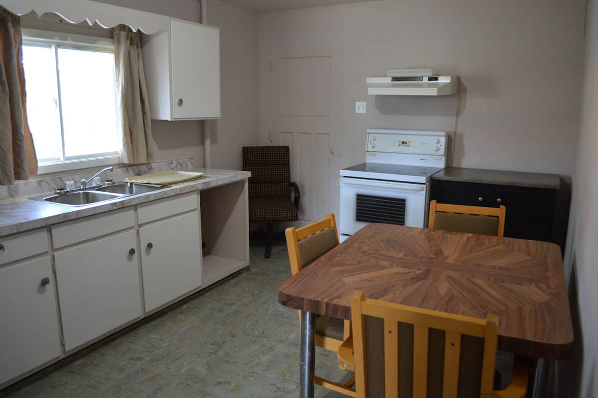 Cocina compacta con lavamanos, estufa y mesa de comedor con sillas.