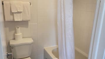 A bathroom with a toilet, a shower with a curtain, and a towel rack with towels.