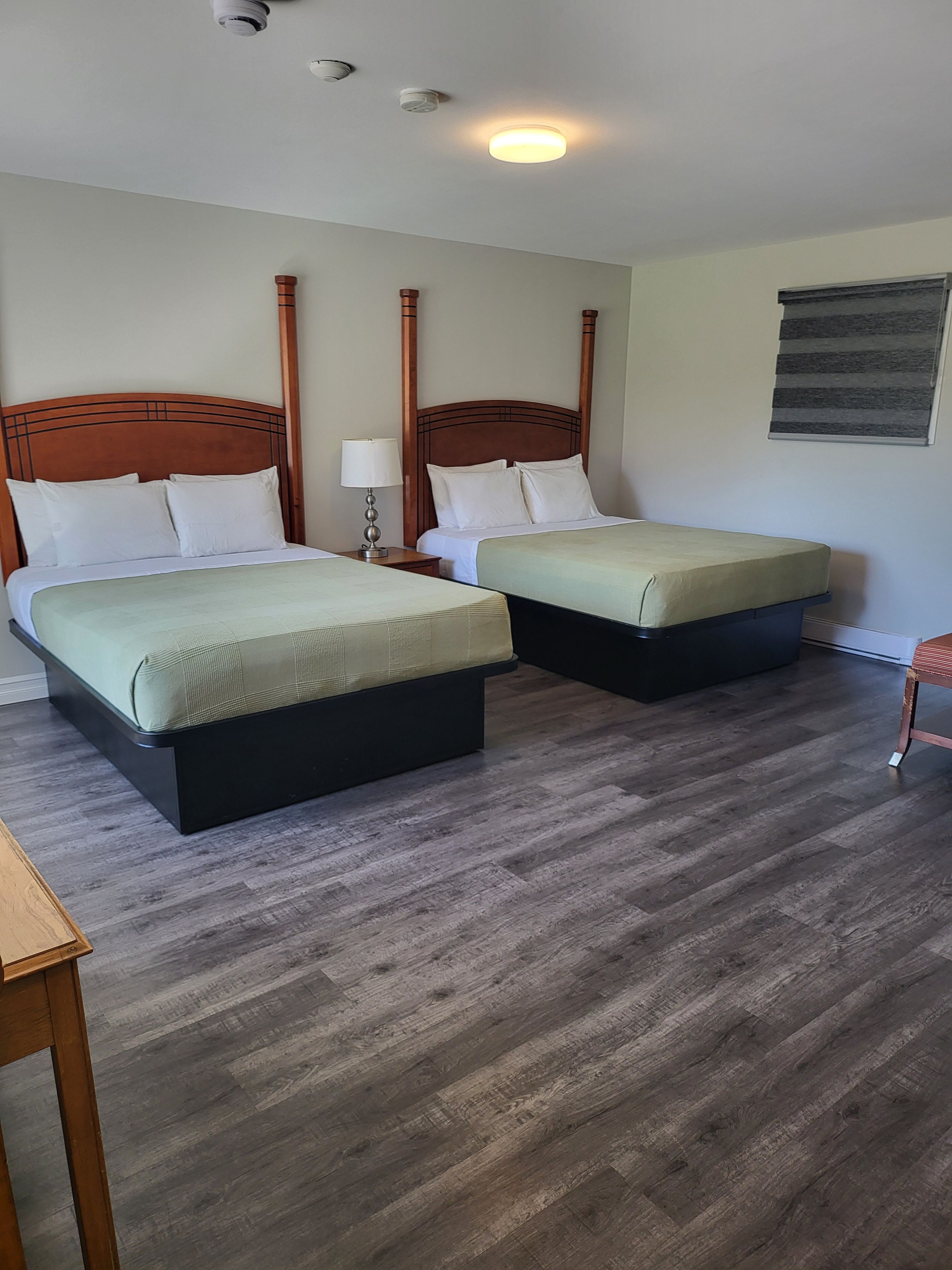 Une chambre d’hôtel avec deux lits, une table de chevet, une lampe et une petite table.