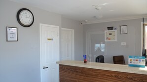 Een receptiebalie met een klok, een welkomstbord en een bordje dat het toilet aangeeft.