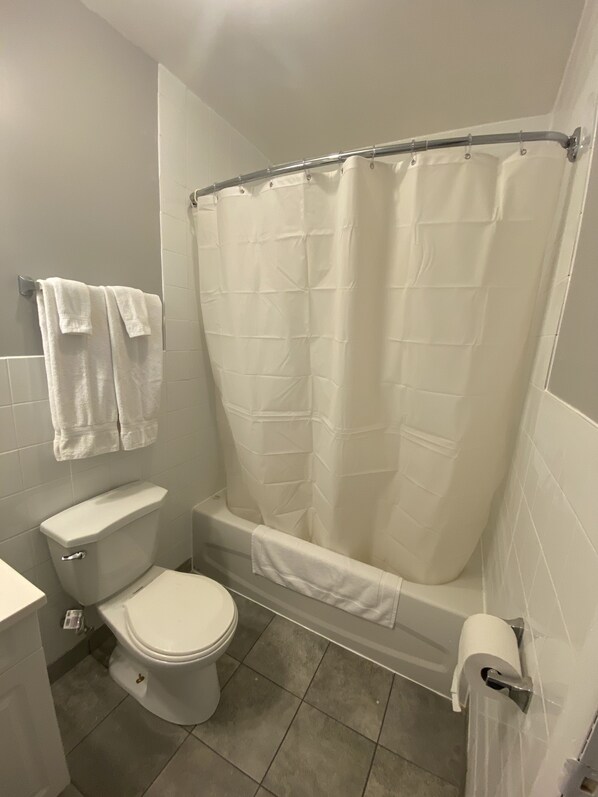 Une salle de bain comprenant des toilettes, une baignoire avec un rideau de douche et un porte-serviettes.