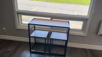 Een kamer met een groot raam, een houten vloer en een klein tafeltje met twee planken.