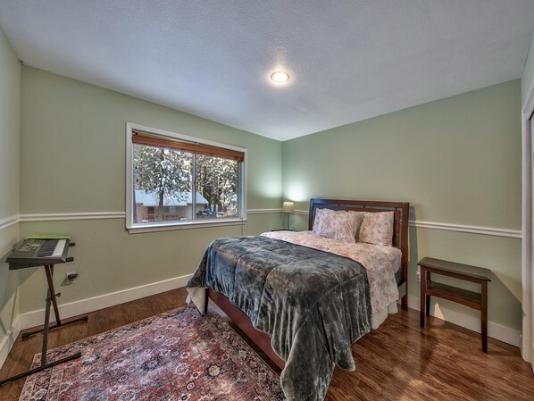 A bedroom with a bed, a window, a lamp, and a small table.