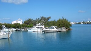 A marina with several boats docked, a white building, and a clear blue sky. - PalmSprings Accommodations - 2 Bedroom Apt., Near Horseshoe Bay (Southampton Parish)