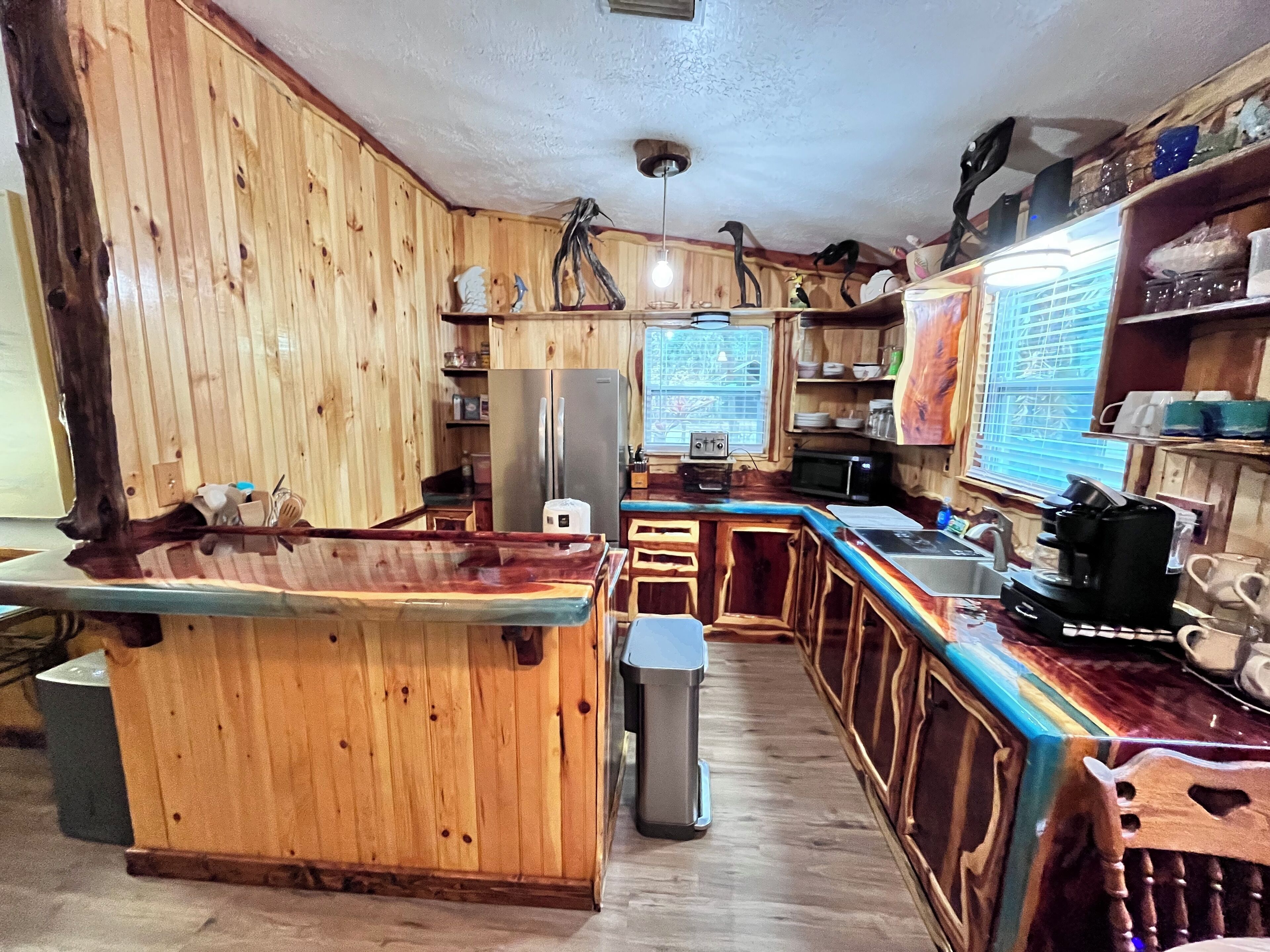 A kitchen with wooden cabinets, a refrigerator, a microwave, and a coffee maker.