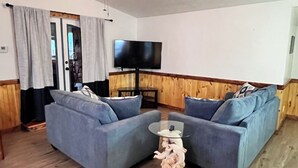 Un soggiorno con due divani, una televisione e un pavimento in legno.