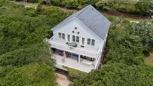 A two-story house with a balcony, surrounded by dense greenery. - Captain’s Quarters - Private Beach Access! (Atlantic Beach)