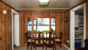 Un comedor con una mesa y sillas, vista a un lago y paredes de madera.