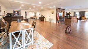Un amplio hall de hotel con un mostrador de recepción de madera, una gran mesa de comedor y una chimenea.