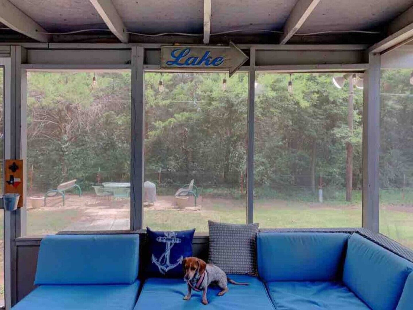 A covered outdoor seating area with a view of a lake and greenery.