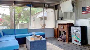 A covered outdoor seating area with blue sofas and a wicker coffee table.