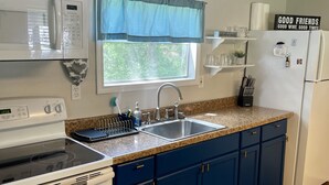 A kitchen with a stove, microwave, sink, and refrigerator.