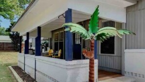 A house with a covered porch, a palm tree, and a small garden area.