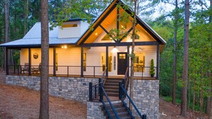 Une cabane avec des fondations en pierre, une terrasse en bois et un escalier menant à l’entrée.