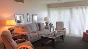 Ein Wohnzimmer mit einer Couch, Sesseln, einem Couchtisch und einem Deckenventilator.