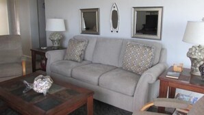 Ein Wohnzimmer mit grauem Sofa, zwei Beistelltischen mit Lampen und einem Couchtisch.