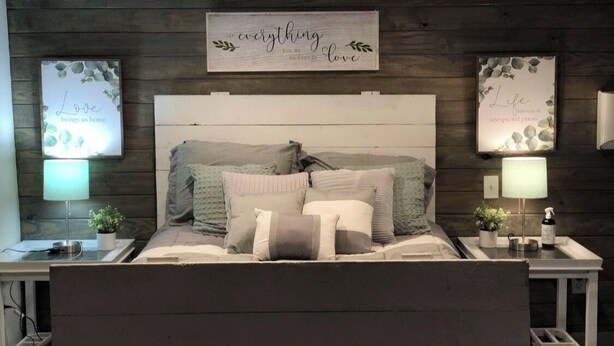 A bedroom with a wooden headboard, multiple pillows, bedside tables with lamps, and decorative wall art. - PET FRIENDLY MAIN STREET LOFT, WALKING DISTANTANCE TO OLD TOWN TOMBALL (Tomball)