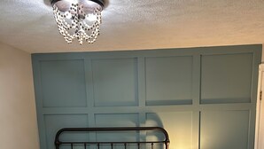 A bedroom with a bed, a nightstand with a lamp, and a ceiling light fixture.