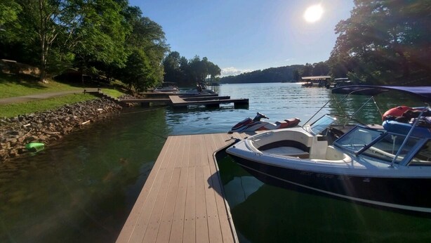 A calm lake with boats docked at a wooden pier, surrounded by trees and a clear sky. - Lakefront Home in Private Cove of Deerfield Resort with Boat Slip. Pet-Friendly! (LaFollette)