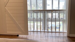 A room with a large sliding barn door, a ceiling fan, and a view of a deck with outdoor furniture. - Lakefront Home in Private Cove of Deerfield Resort with Boat Slip. Pet-Friendly! (LaFollette)