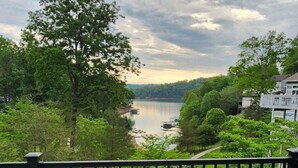 A deck with a round table and two chairs, overlooking a river and greenery. - Lakefront Home in Private Cove of Deerfield Resort with Boat Slip. Pet-Friendly! (LaFollette)