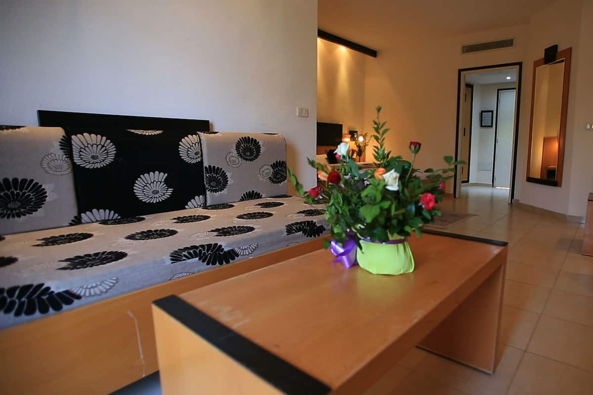 A living room with a sofa, a coffee table, and a flower vase.