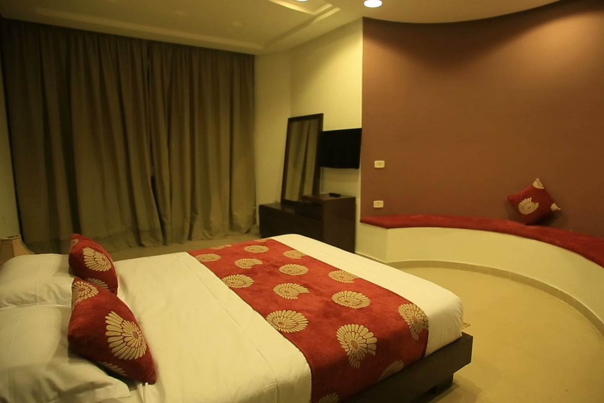 A hotel room with a bed, a desk, and a curved wall.