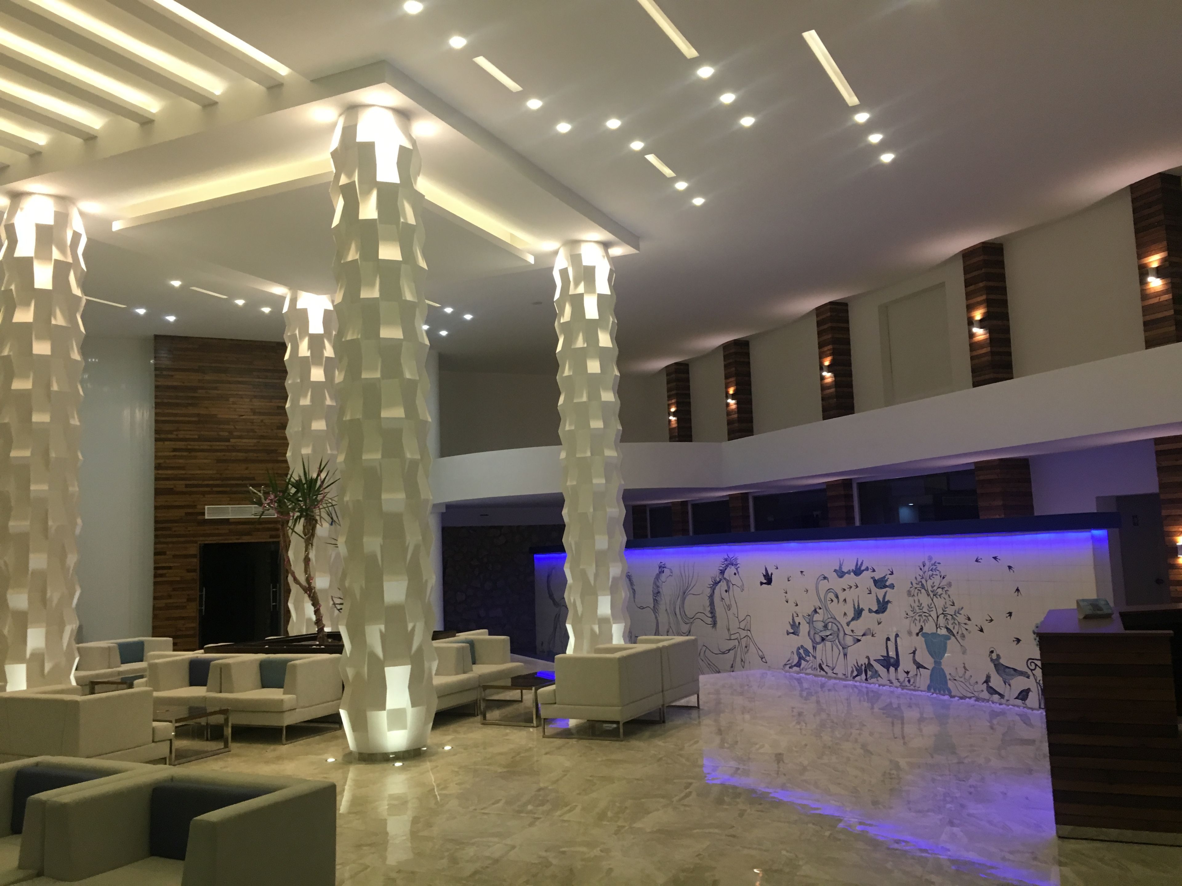 A modern lobby with high ceilings, recessed lighting, and a reception desk.