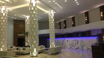 A modern lobby with high ceilings, recessed lighting, and a reception desk.