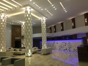 A modern lobby with high ceilings, recessed lighting, and a reception desk.