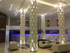 A modern lobby with a central seating area, a pool table, and decorative light fixtures.