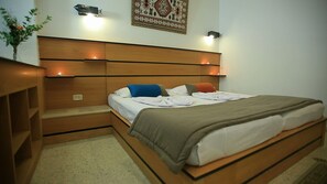 A hotel room with a wooden headboard, a bed with white bedding, and a small bedside table.