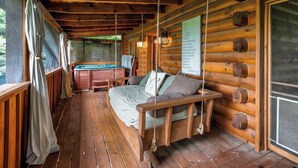 Una cabaña acogedora con terraza de madera, una silla mecedora, mesa de billar y jacuzzi.